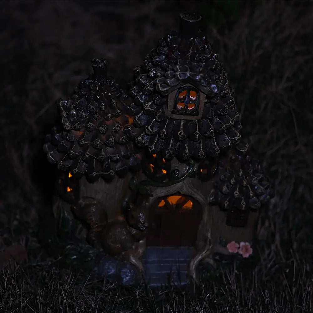 Solar fairy house with pinecone roof glowing at night garden decor