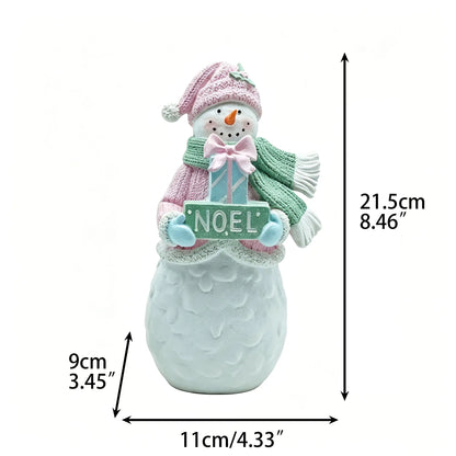 Female snowman figurine with pink knit beanie, green scarf, and NOEL gift sign, 21.5cm tall, front view with dimensions